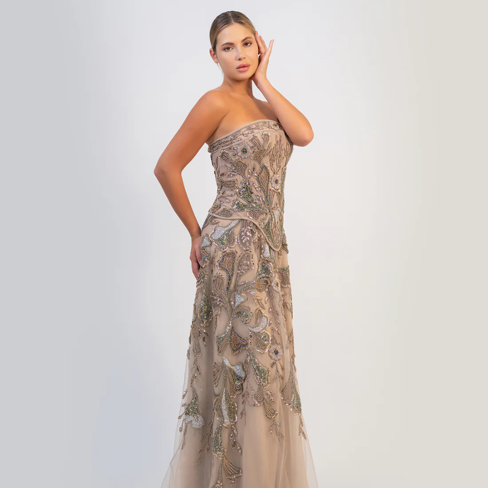 Shop online soft mocha strapless gown with fitted bodice, flowing silhouette and intricate shimmering embellishments, perfect for parties and special occasions.