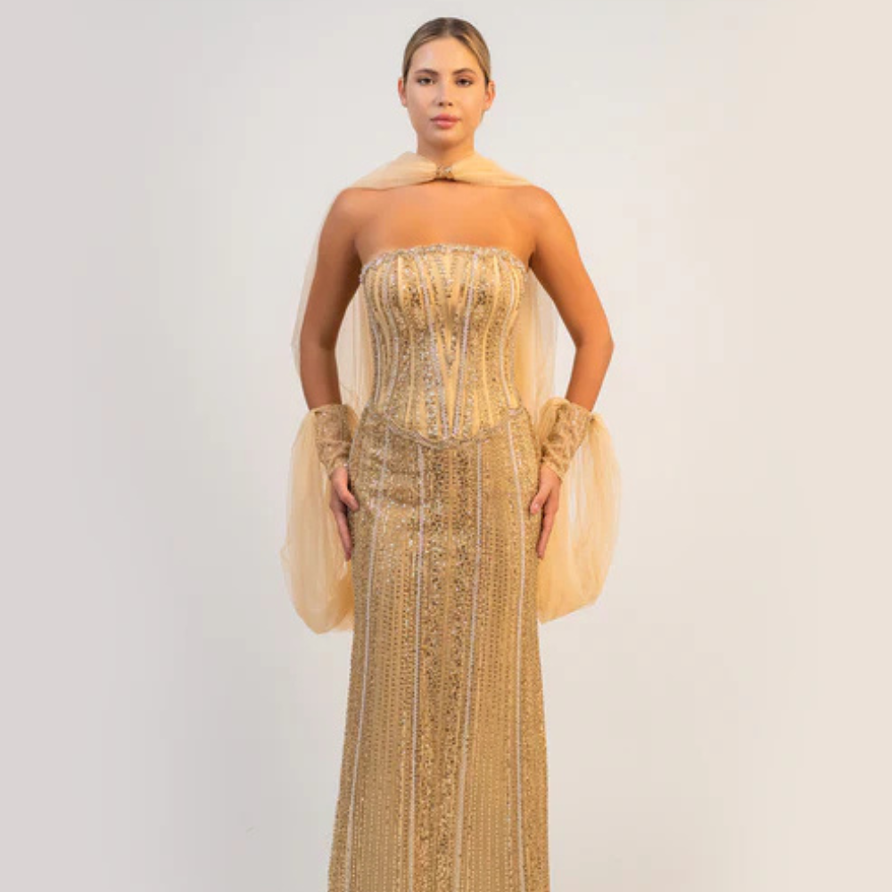 Shop online dazzling gold gown with sparkling corset, sleek silhouette and flowing cape-inspired details, perfect for parties and special occasions.