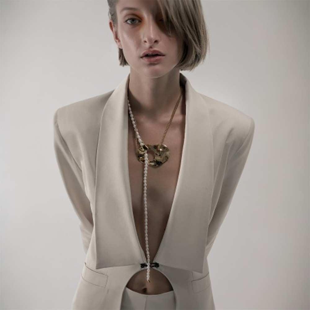 Long pearl and chain necklace with oversized reflective surface detail.