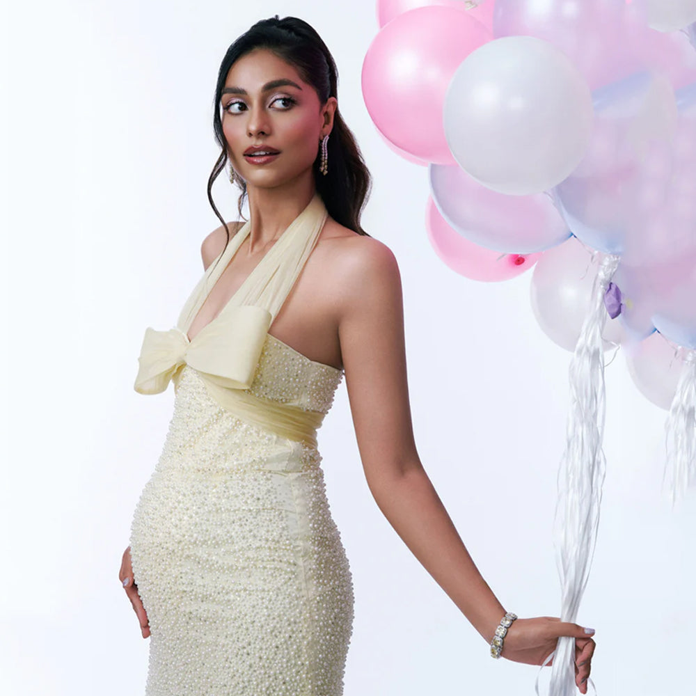 Butter yellow maternity gown with pearl sequin detail and halter neck, perfect for baby showers. Shop online from our curated edit of premium fashion.