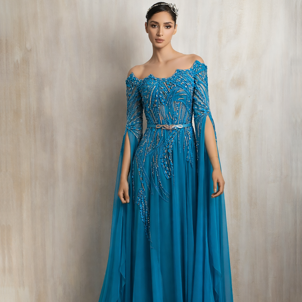 Turquoise embellished gown with a graceful flowing cape, designed for elegant evening occasions. Shop now at our exclusive clothing website.
