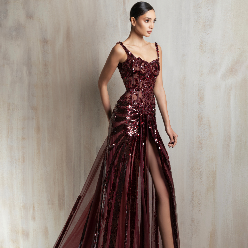 Burgundy sequined gown with sheer panels and a high slit, crafted for glamorous evening occasions. Shop now at our exclusive clothing website.