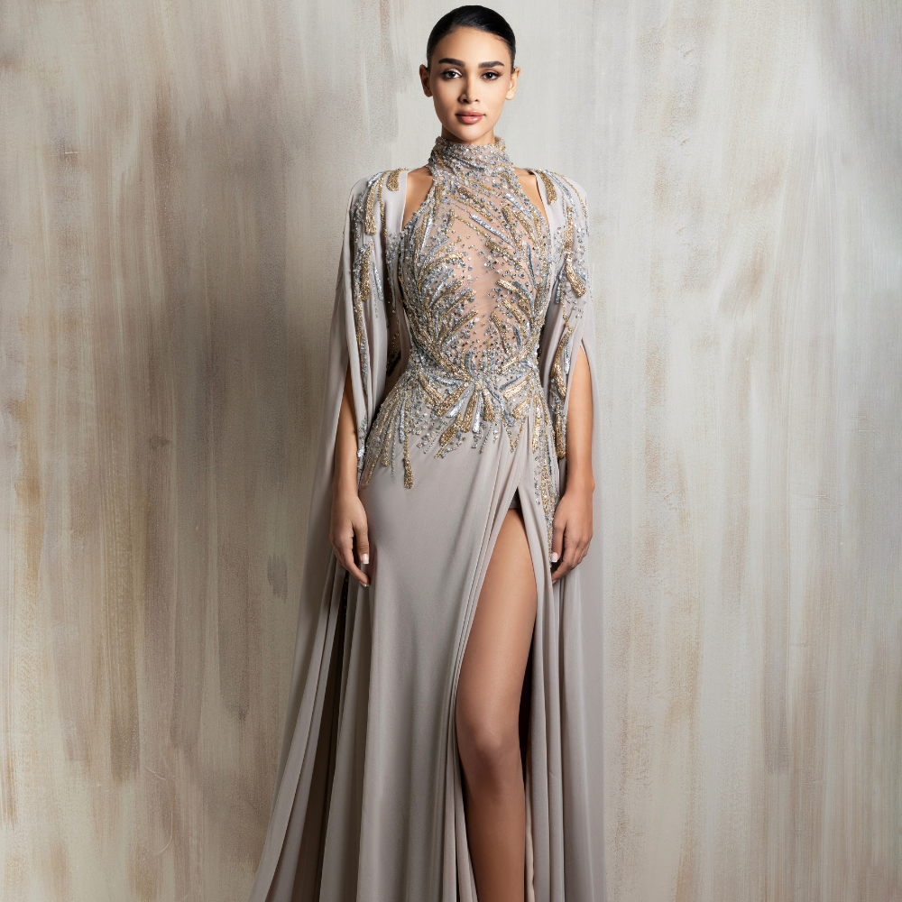Taupe embellished gown with a high slit and flowing cape sleeves, designed for effortless elegance. Shop now at our exclusive clothing website.