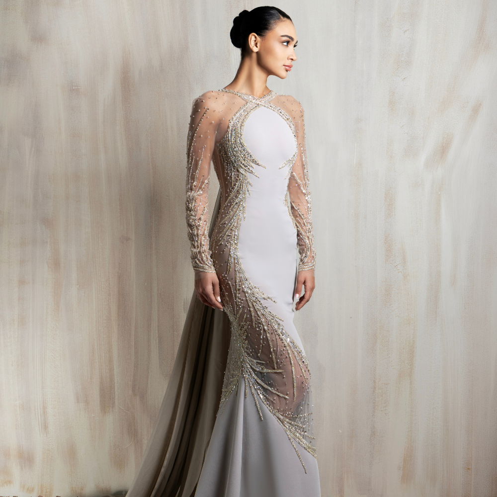 Light grey illusion gown with gold embellishments and a fitted silhouette, crafted for timeless elegance. Shop now at our exclusive clothing website.