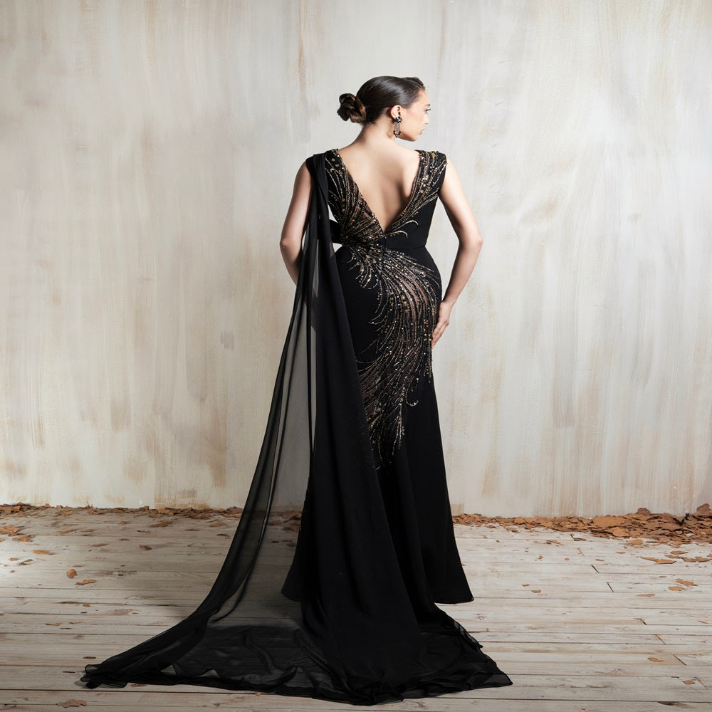 Black gown with golden cascade embroidery and a sleek flowing cape, crafted for glamorous evening events and special occasions. Shop now at our exclusive clothing website.