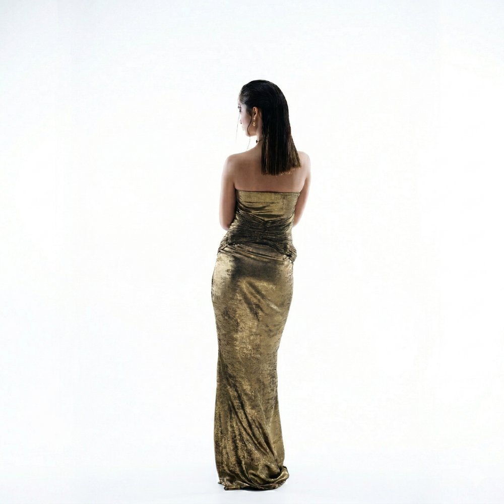 Woman wearing a gold strapless gown on a white background