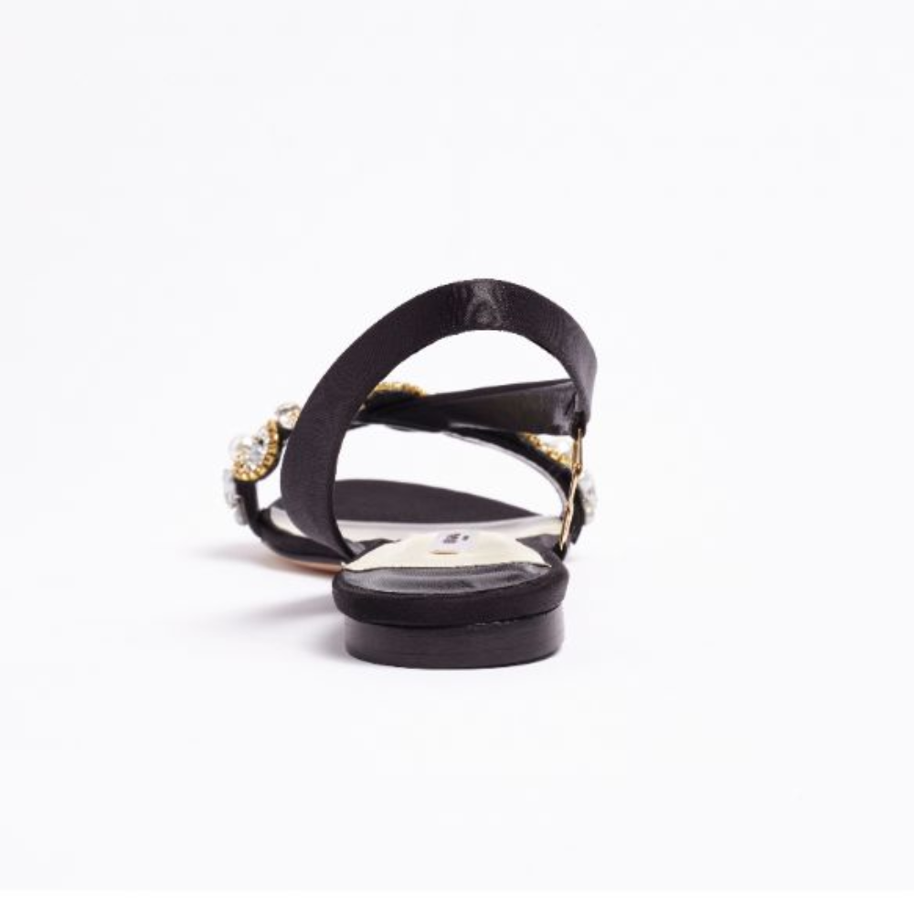 The L’Amazone Mon Bijoux flat sandal is designed in rich black double satin adorned with embellishments at its toe band.