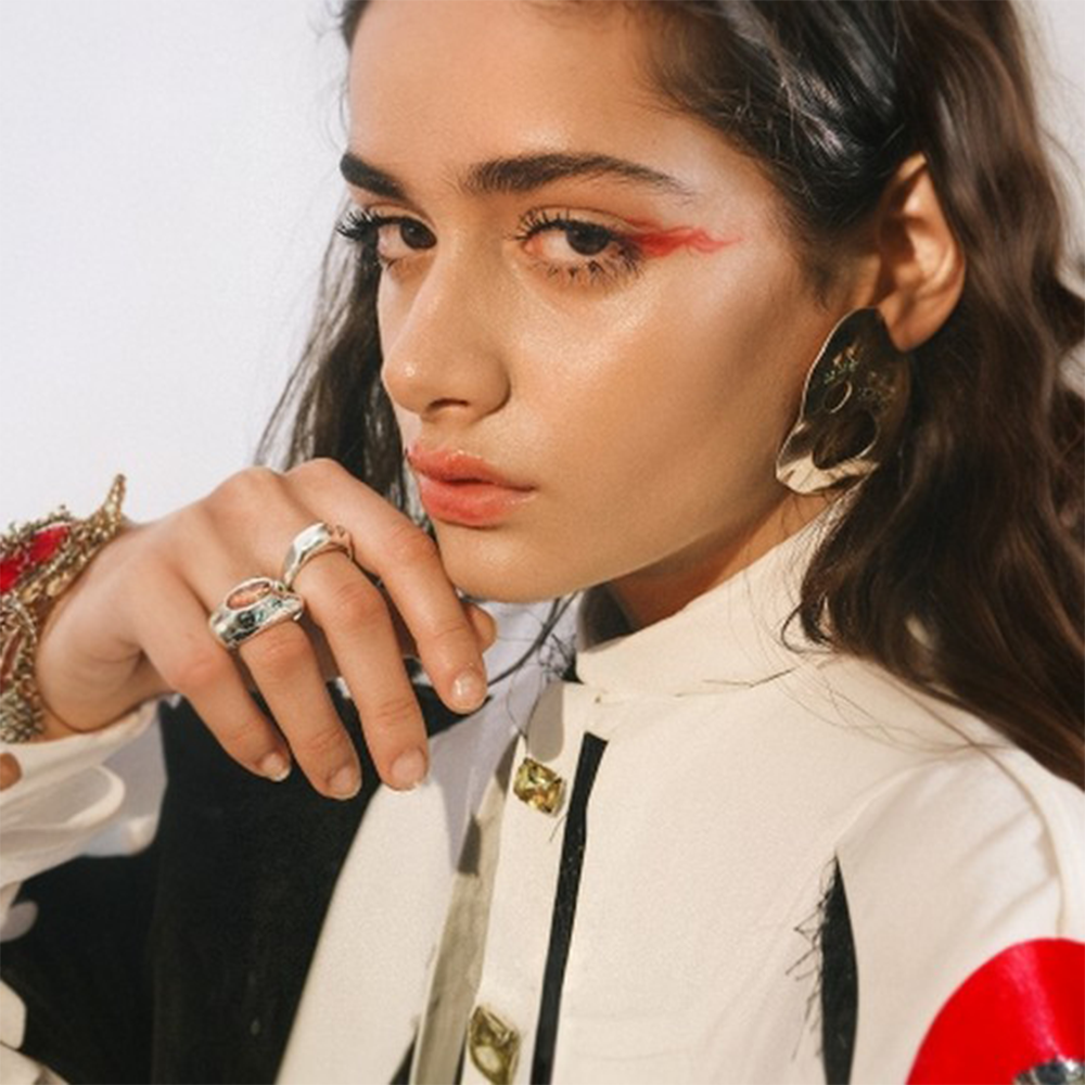 Statement earrings embellished with multi colored zircon stones on reflective surface.