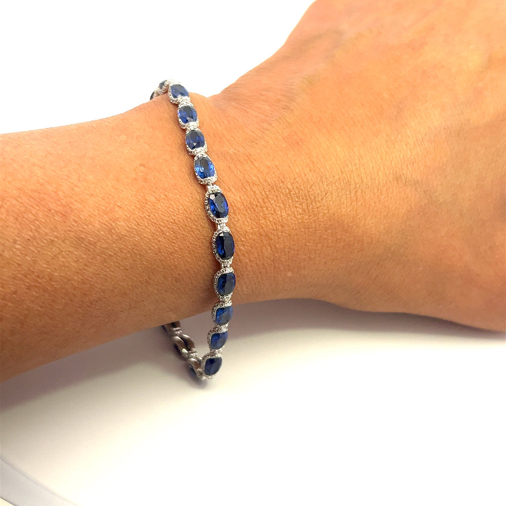 Sterling silver rhodium plated tennis bracelet featuring oval lab-created blue sapphires surrounded by sparkling cubic zirconia for a timeless statement look. Shop premium jewelry online.
