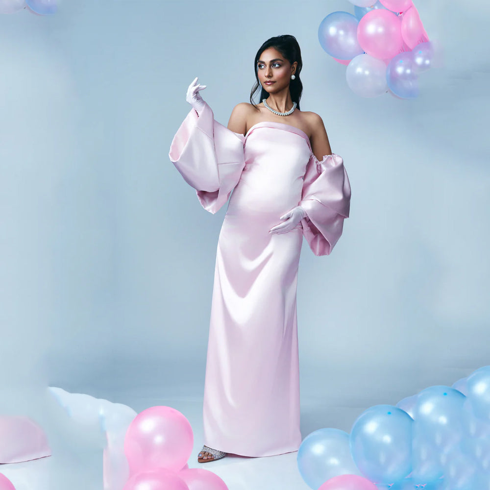 Blush pink satin maternity dress with off shoulder sleeves and A-line fit, perfect for baby showers. Shop online from our curated edit of premium fashion.