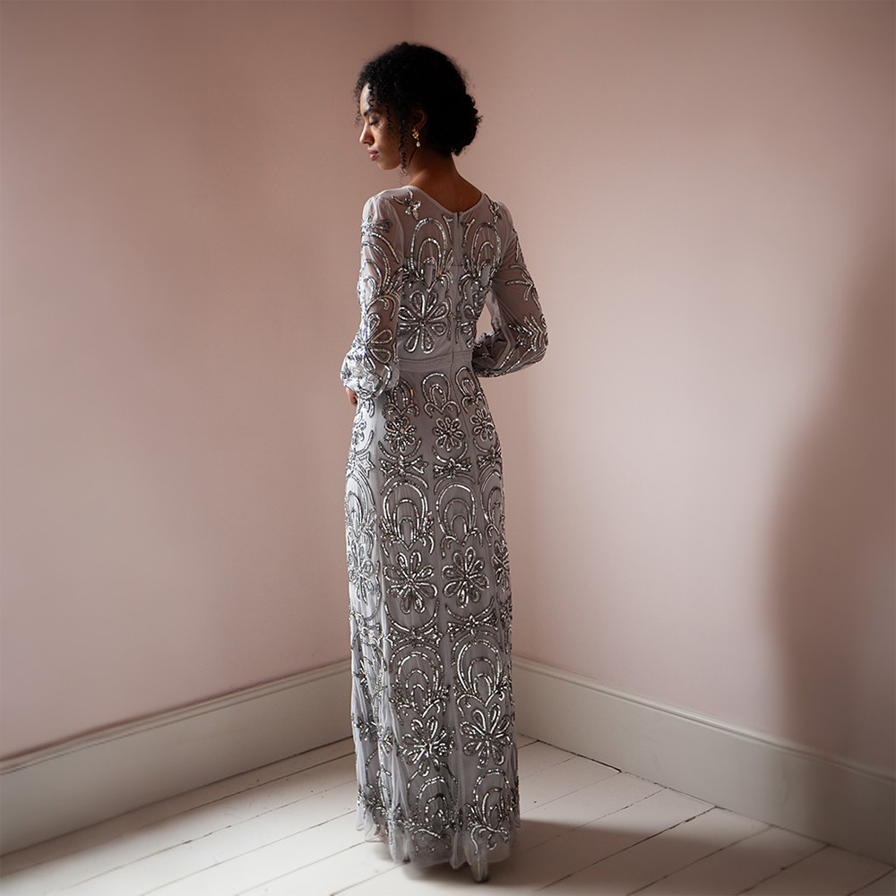 Elevate your look with the breathtaking silver floor-length gown adorned featuring mesh sleeves and a neckline.