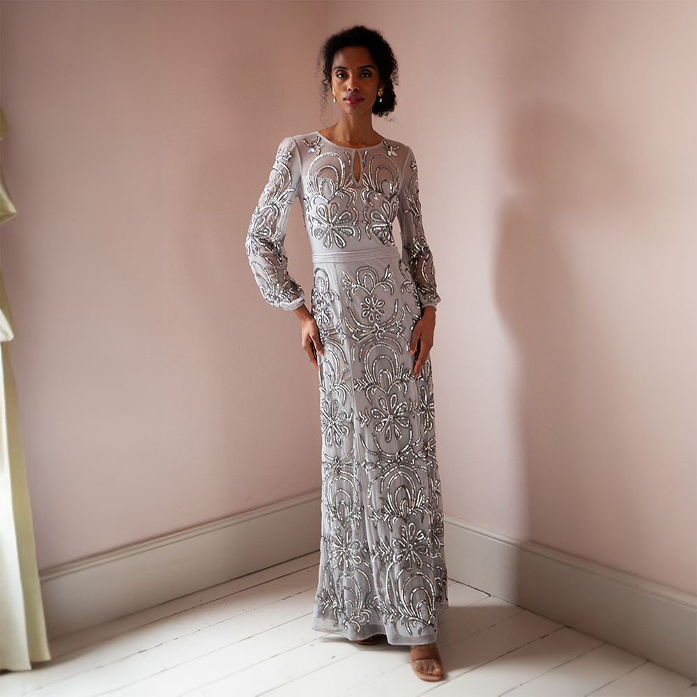 Elevate your look with the breathtaking silver floor-length gown adorned featuring mesh sleeves and a neckline.