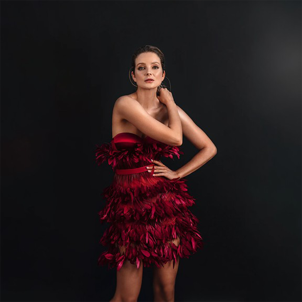 A deep saturated burgundy corseted mini dress in silk satin and ruffled feathers.