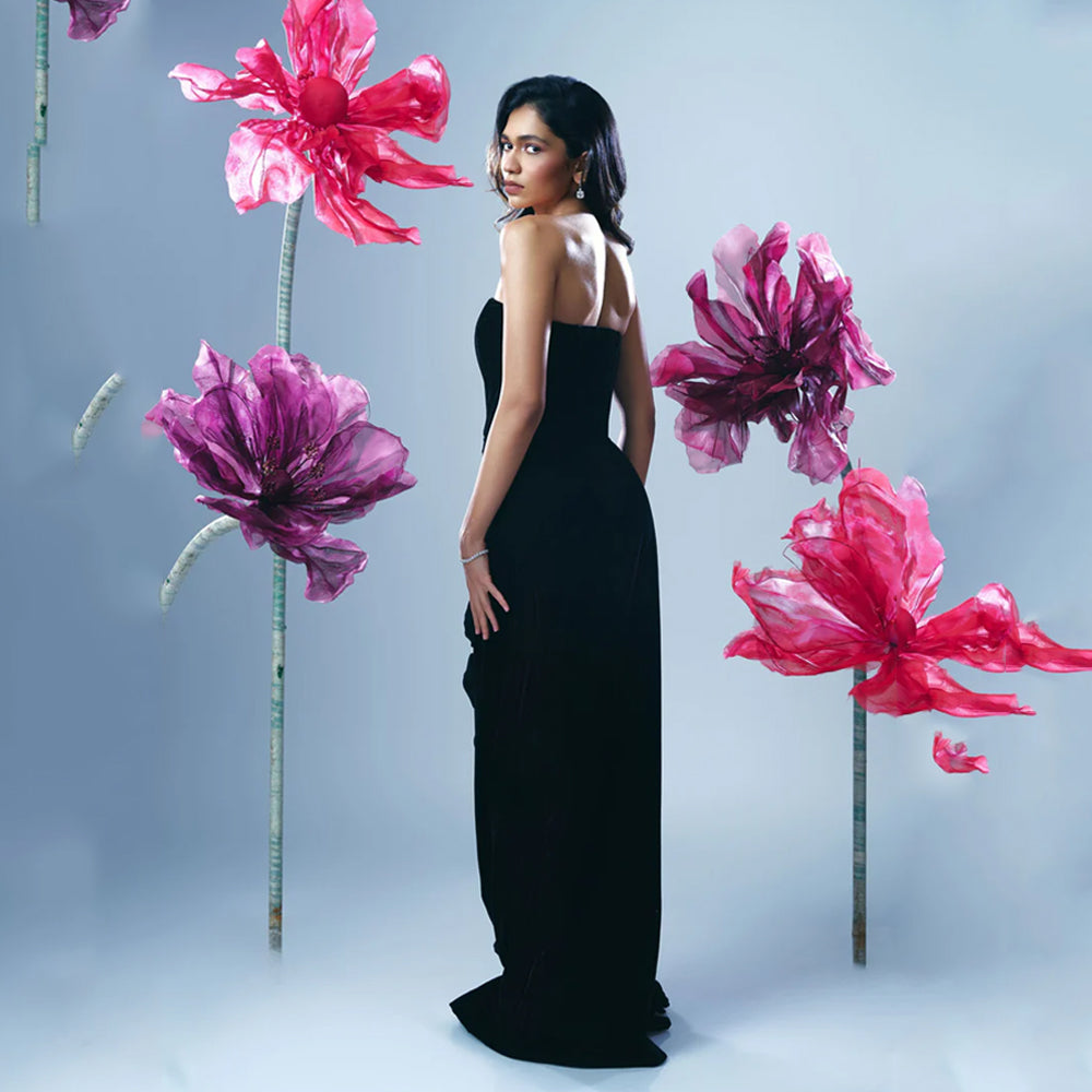 Black velvet corset gown with slit and rose detail, perfect for evening events. Shop online from our curated edit of premium fashion.