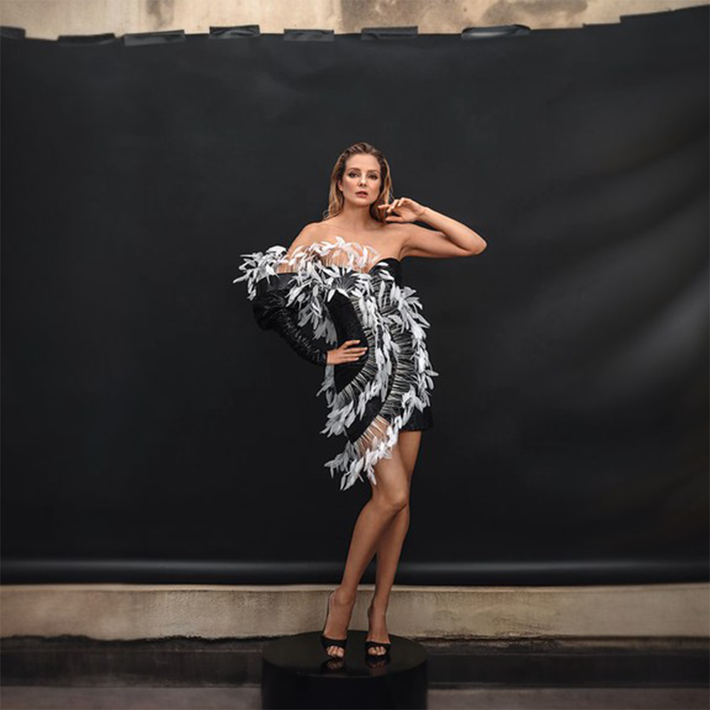 A mini dress in jet black sequins highlighted with a halo in white coq plumes.
