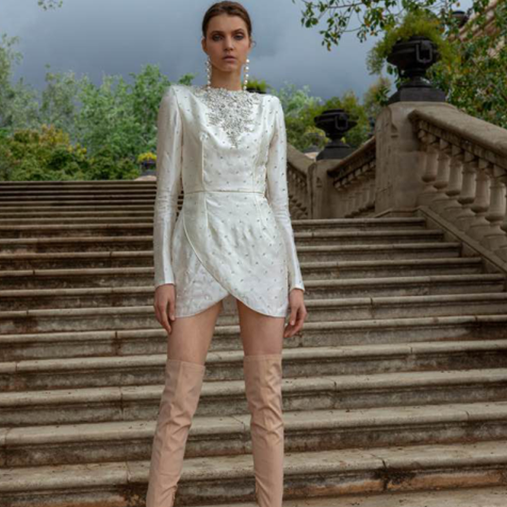 Dress made in satin with shoulder pads, long sleeves, open back and wrap skirt.