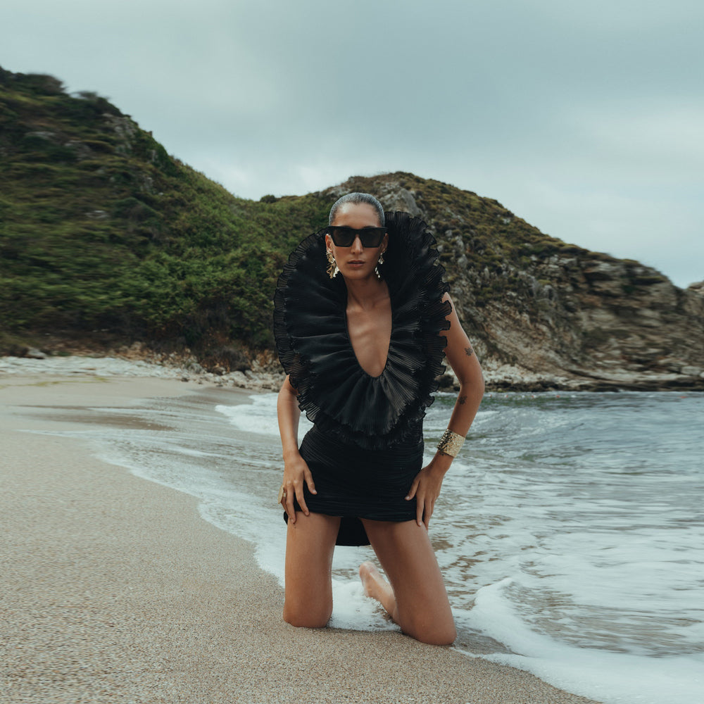 Shop online from our exclusive website and discover the Lale Dress by Nana Gotti, a black chiffon pleated bodycon mini dress with an oversized ruffle collar for a bold, elegant statement.
