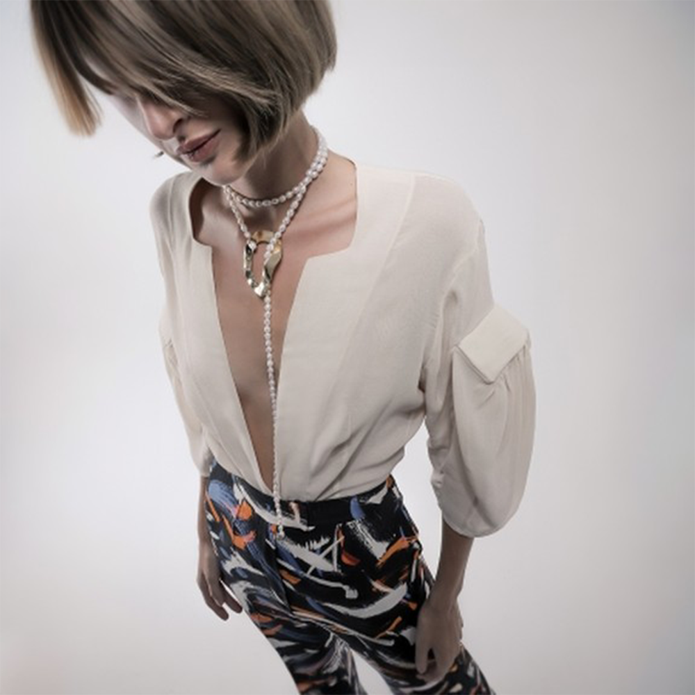 Long pearl necklace with oversized reflective surface detail.