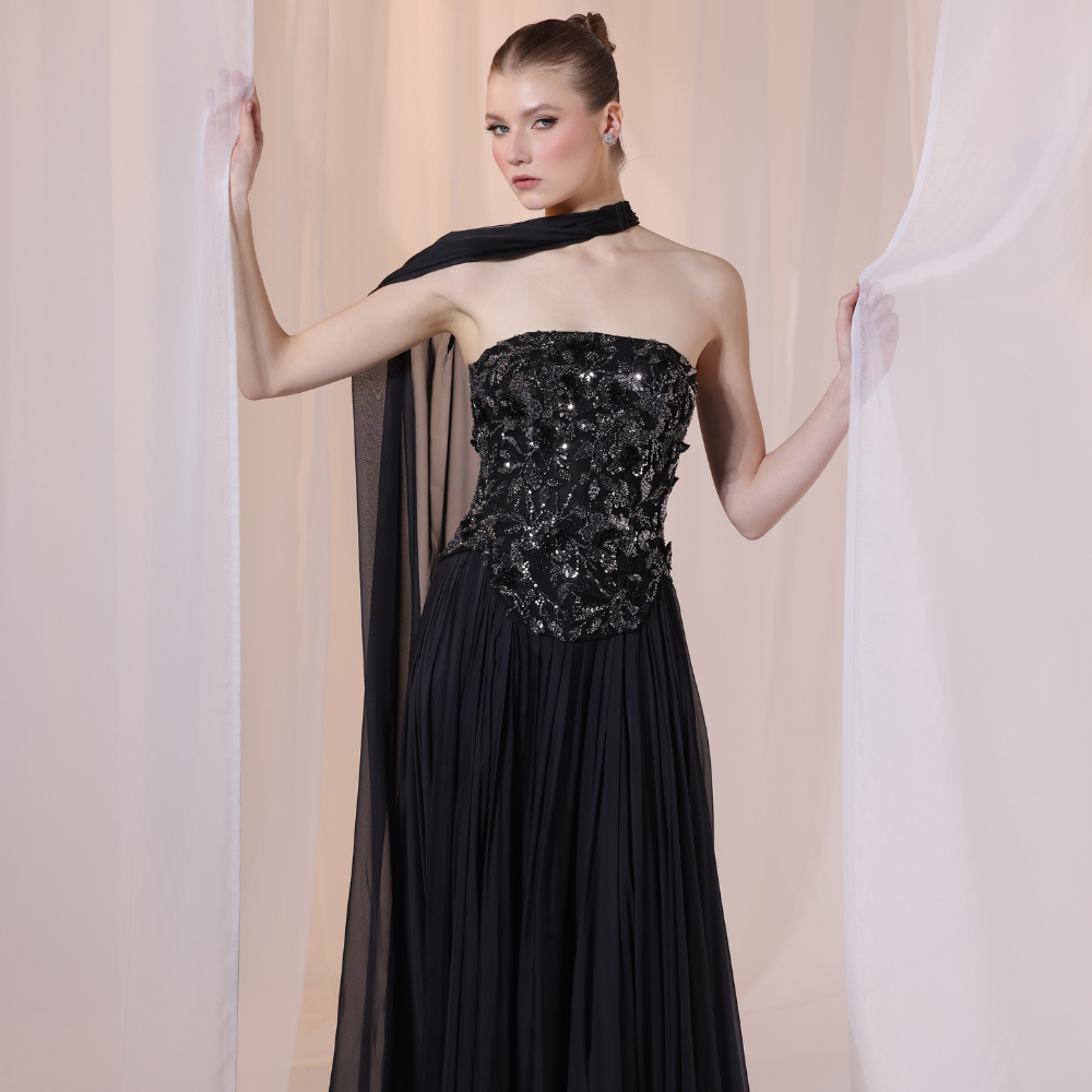 Shop online black gown with embellished strapless bodice, flowing silhouette and sheer one-shoulder drape, perfect for parties and special occasions.