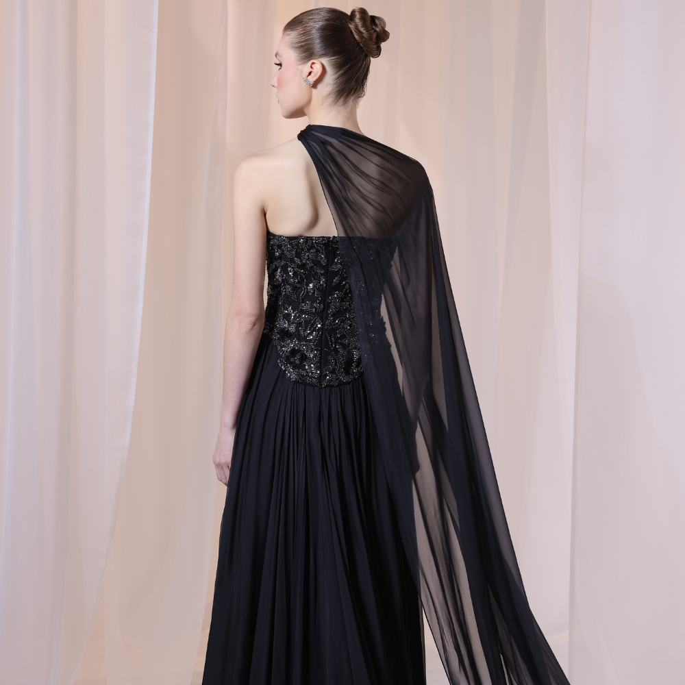Shop online black gown with embellished strapless bodice, flowing silhouette and sheer one-shoulder drape, perfect for parties and special occasions.