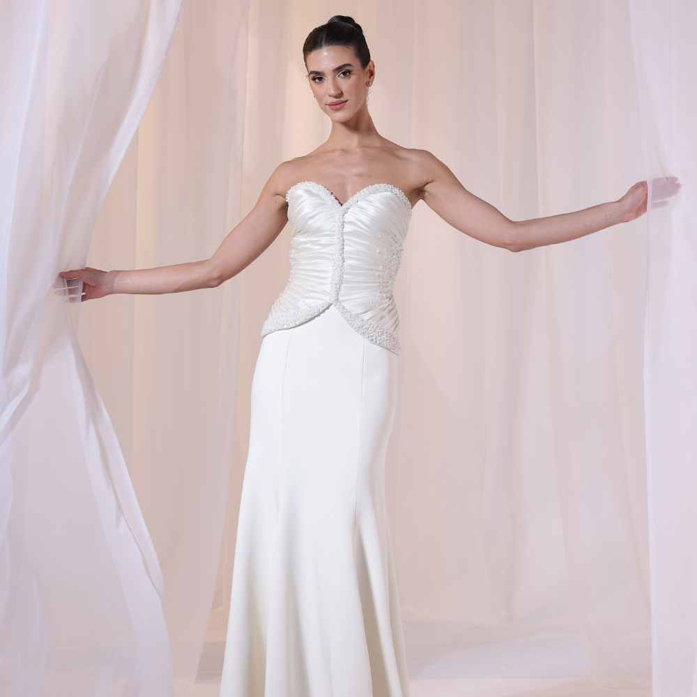 Shop online timeless ivory gown with structured corset, delicate ruching and flowing silhouette, perfect for weddings, receptions and special occasions.