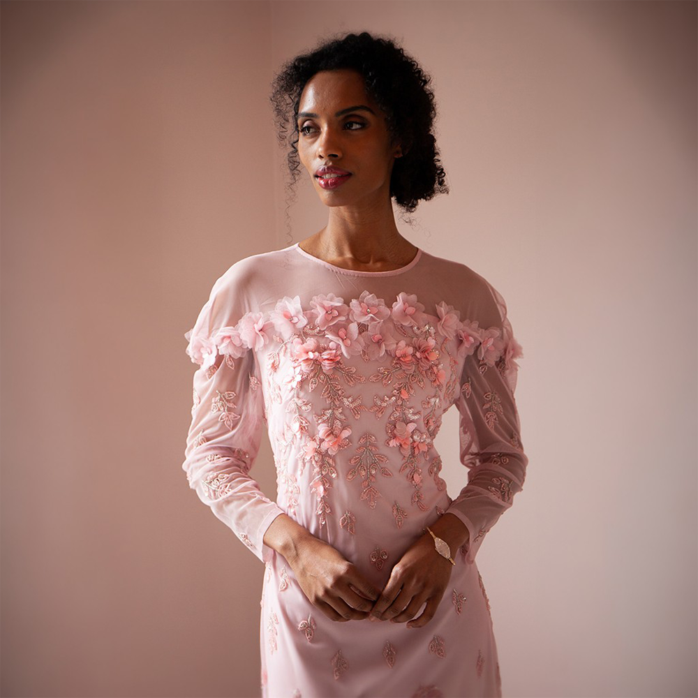 The Maddy Gown is floor length with a sheer neckline and full-length sheer sleeves.