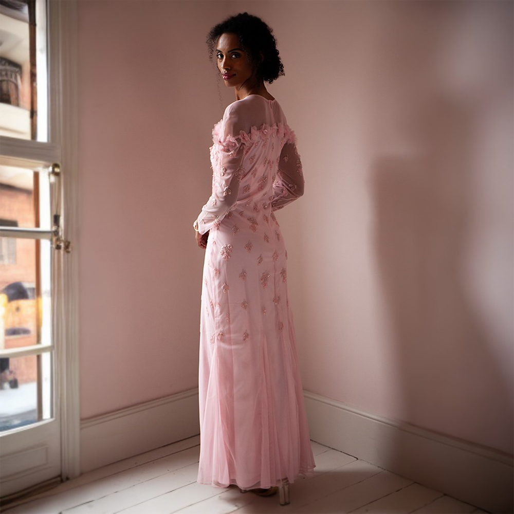 The Maddy Gown is floor length with a sheer neckline and full-length sheer sleeves.