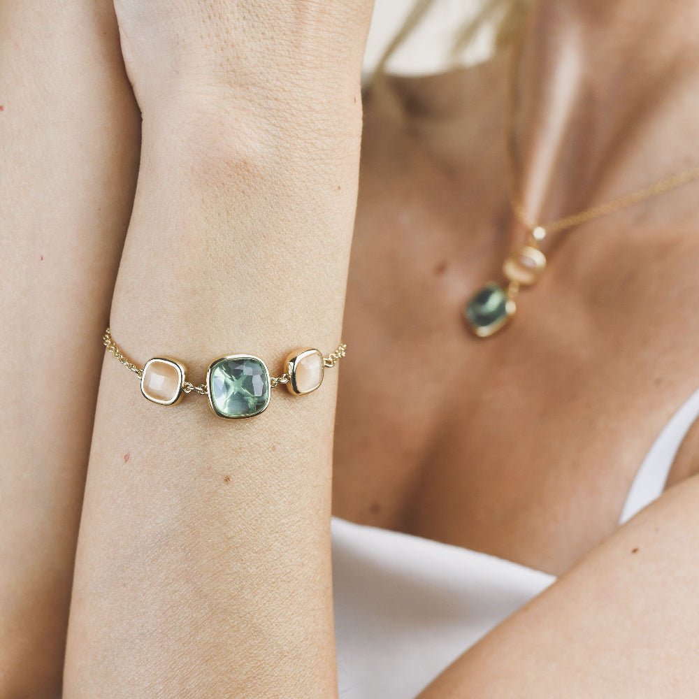 Yellow gold plated bracelet with a striking aquamarine crystal and peach-toned crystal accents for a stylish modern touch. Shop premium jewelry online.