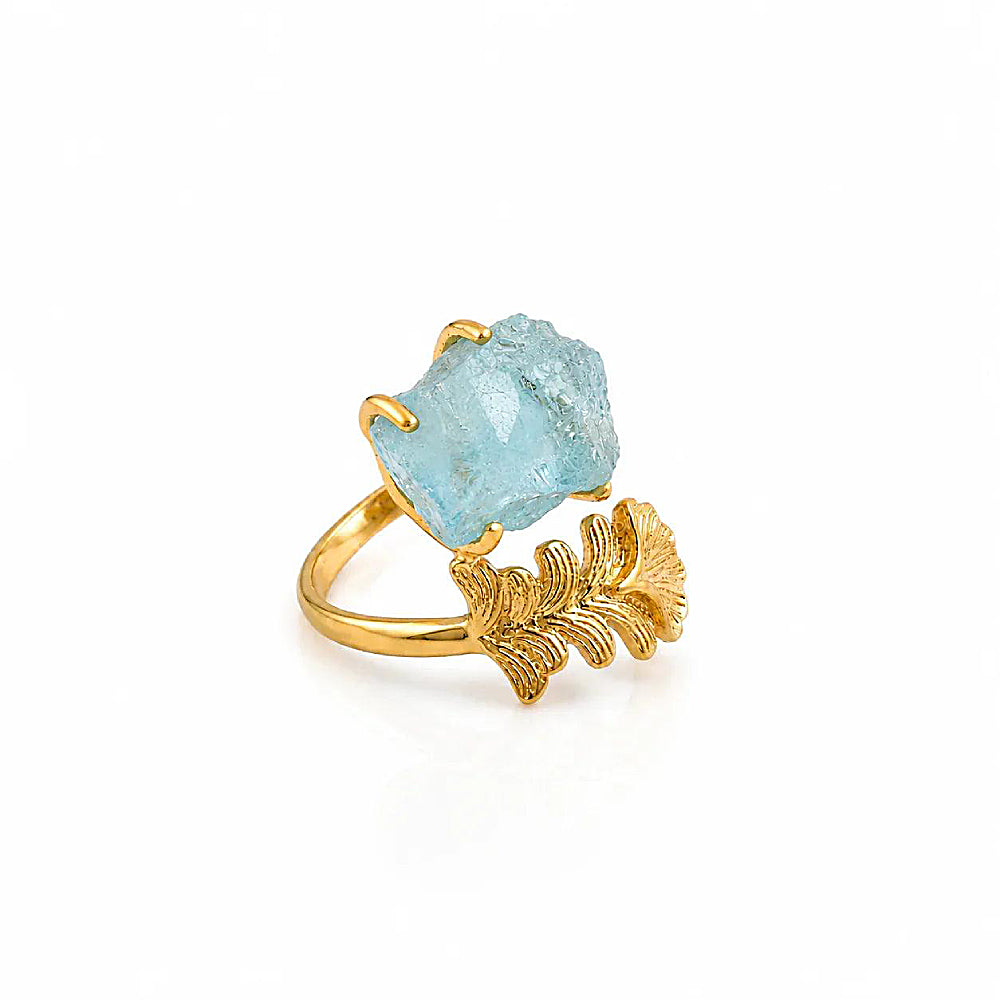 Discover the Nymph Aquamarine Gold Leaf Ring at The Luxe Maison, featuring a raw aquamarine gemstone held in golden prongs and framed by a sculptural gold leaf design. Inspired by mythical forest and water nymphs, this nature-inspired ring combines soft blue hues with organic elegance for a distinctive, enchanting look.