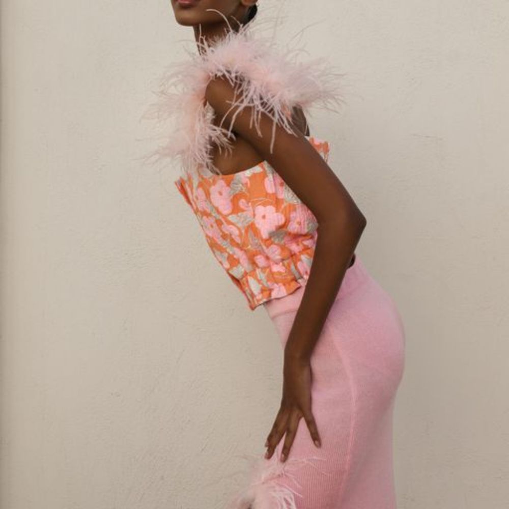 Pink flower top with feather details is designed with pearl bottoms on the front and detachable feather details.