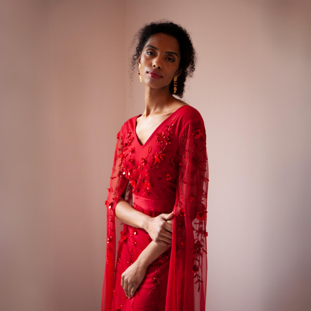 The Betsy Gown is a rich red colour with mesh sleeves that cascade to the floor as well as red floral sequins