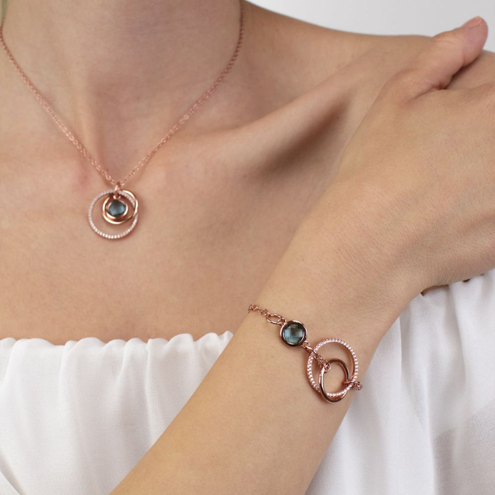 Elegant rose gold plated bracelet with concentric circle detailing, sparkling cubic zirconia, and a sky blue crystal accent. Perfect for luxe everyday styling. Shop premium jewelry online.