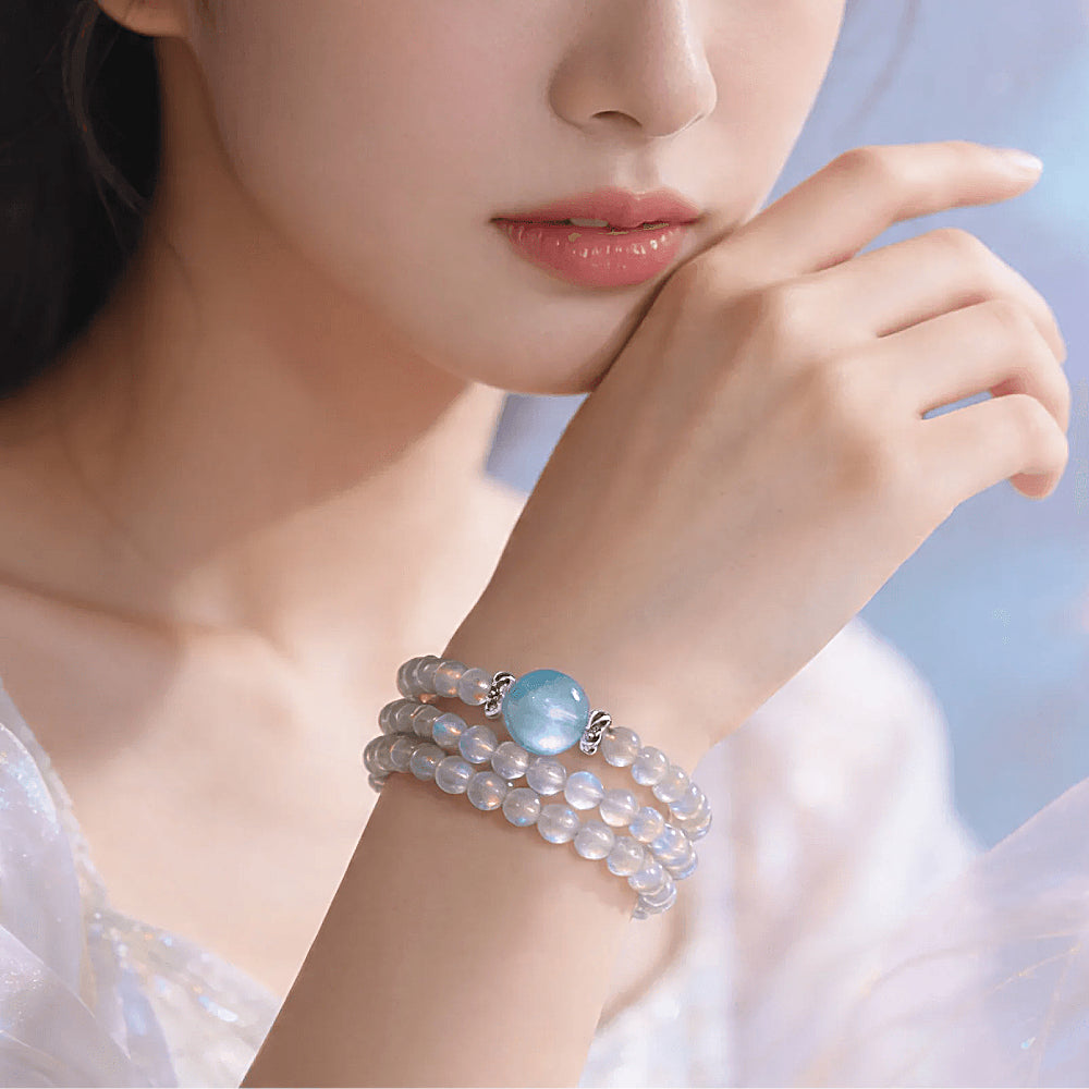 Discover the Selene Gray Moonstone & Aquamarine Wrap Bracelet at The Luxe Maison, featuring serene gemstones inspired by moonlight and ocean waves.