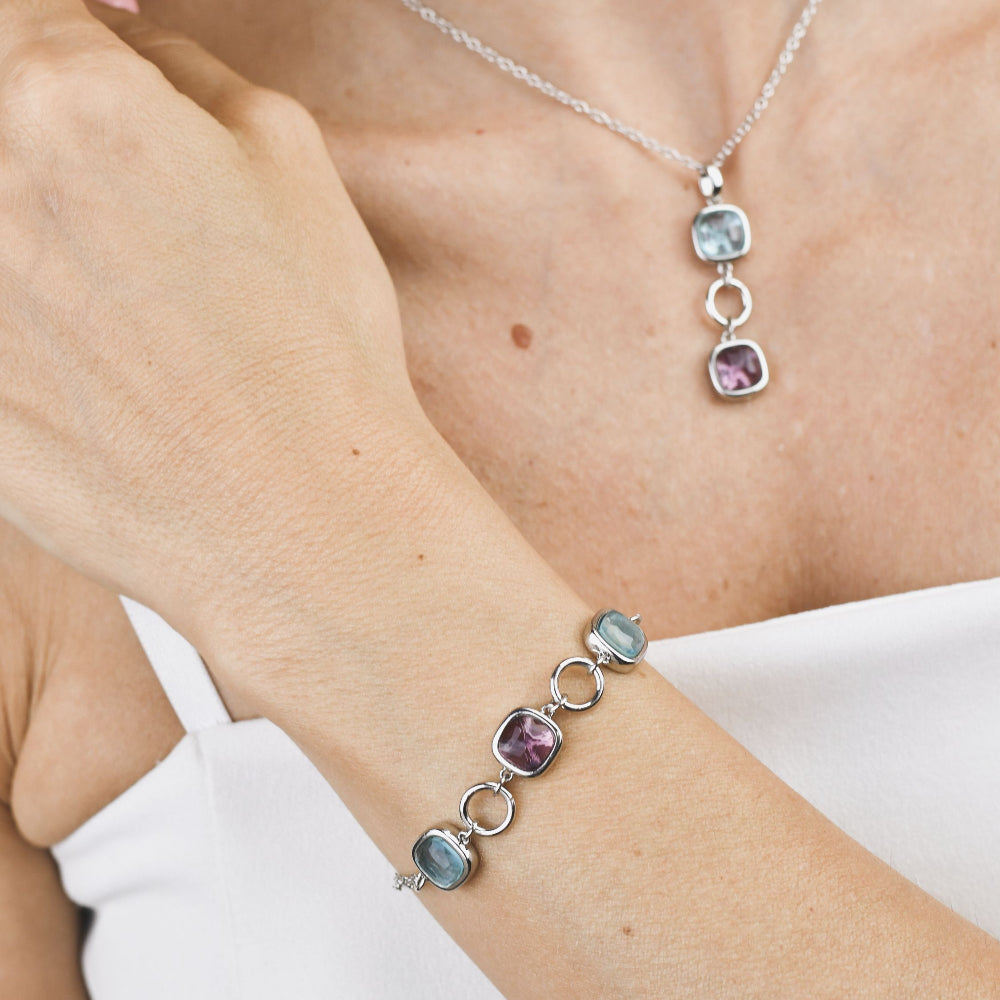 Rhodium-plated bracelet with purple amethyst and milky blue crystal accents, paired with sleek circular modules for a contemporary statement look. Shop premium jewelry online.