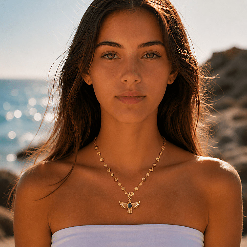 Discover the Soar & Shine Thunderbird Necklace at The Luxe Maison, featuring a radiant gold-tone Thunderbird pendant, a luminous green cat's eye stone, and a delicate sunburst chain for a bold, meaningful touch.