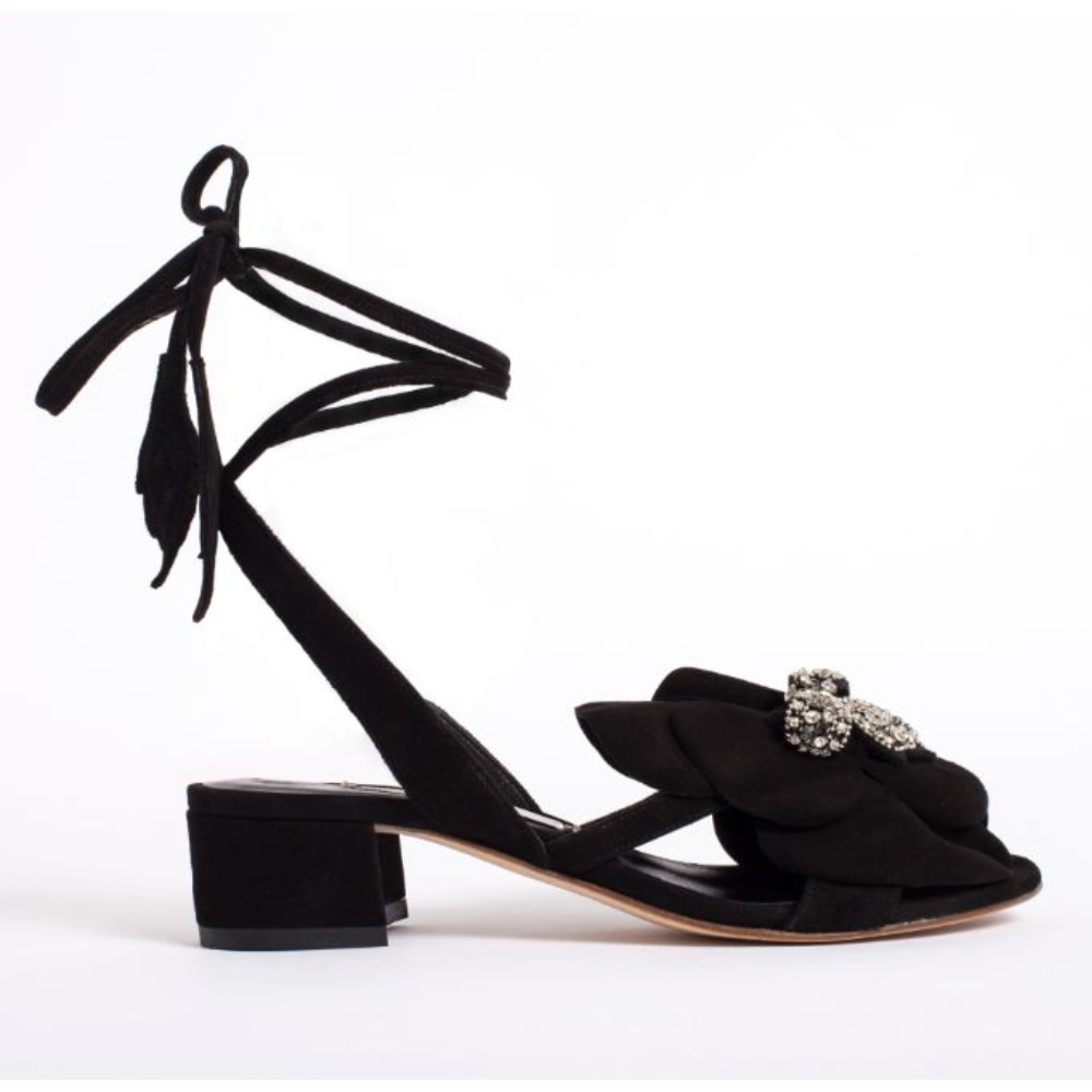 It’s crafted in rich black suede and comes embellished with a bold floral ornament at the front. 