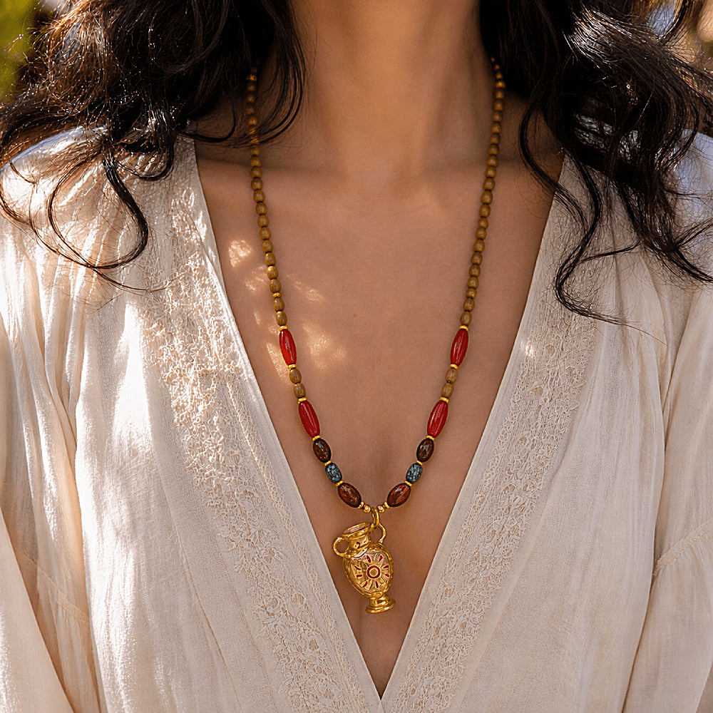 Discover the Sunkeeper Amphora Carnelian Beaded Necklace at The Luxe Maison, featuring a hand-painted golden amphora pendant, a radiant sun motif, and rich carnelian beads for a timeless, Mediterranean-inspired look.
