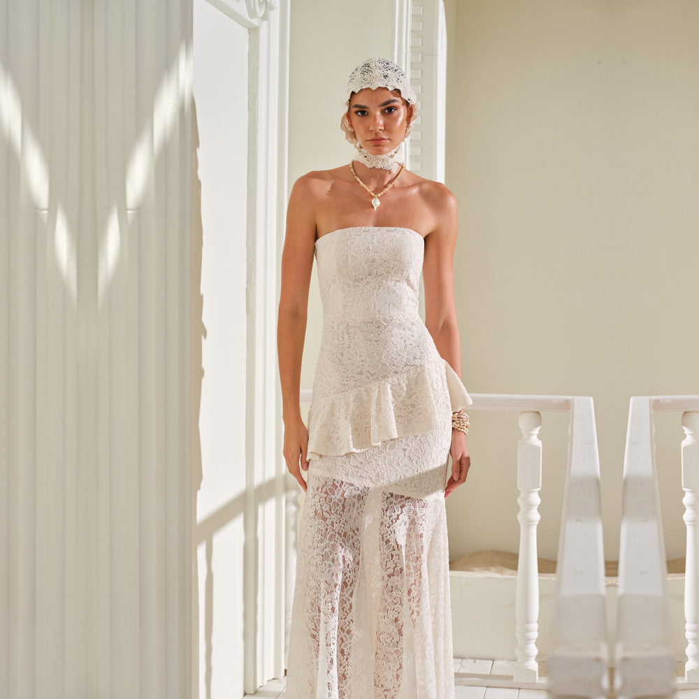 Shop online from our exclusive website and discover the Zephyra Dress by Nana Gotti, a romantic strapless lace dress with a structured bodice and flowing asymmetric layers for timeless elegance.