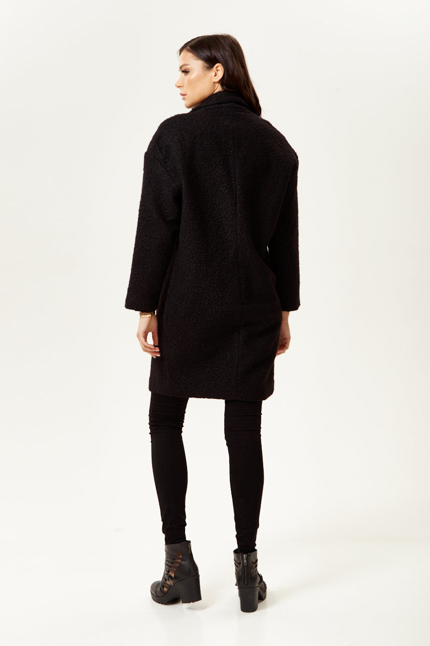 Clothing shop online offering a women’s extra loose fit black bouclé coat for chic layering. Shop Now!