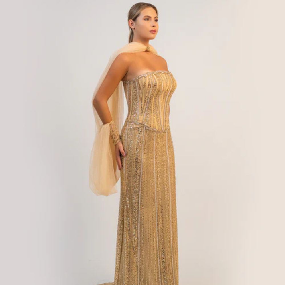 Shop online dazzling gold gown with sparkling corset, sleek silhouette and flowing cape-inspired details, perfect for parties and special occasions.