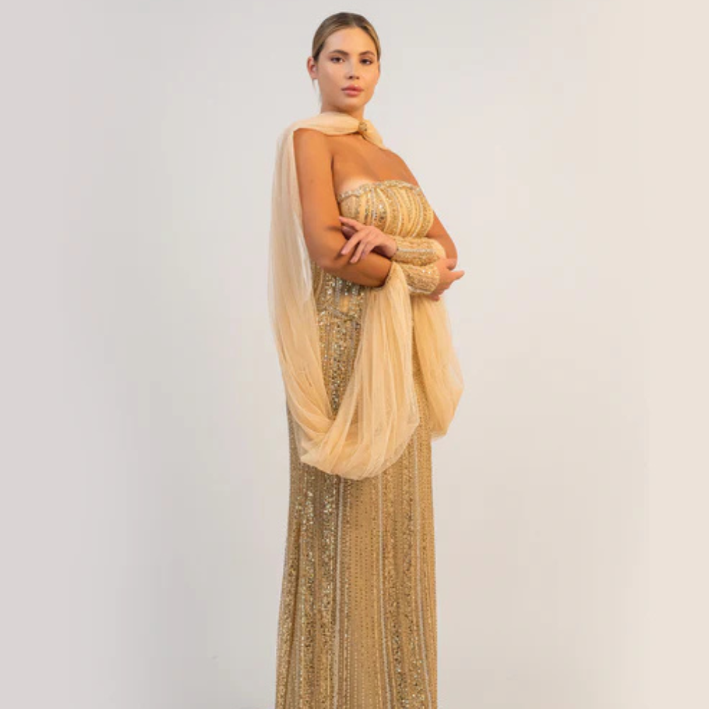 Shop online dazzling gold gown with sparkling corset, sleek silhouette and flowing cape-inspired details, perfect for parties and special occasions.