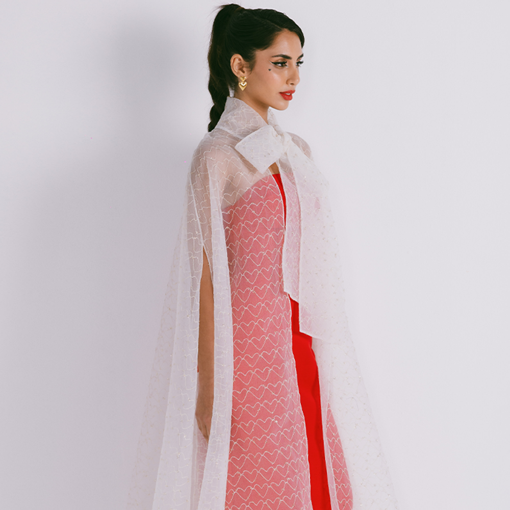 Organza cape with neck bow & heart shaped metallic threads on transparent fabric. Dress sold separately. Explore stylish capes for women. Shop now!