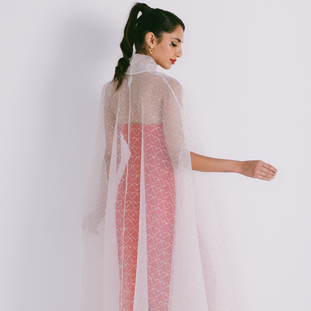 Organza cape with neck bow & heart shaped metallic threads on transparent fabric. Dress sold separately. Explore stylish capes for women. Shop now!