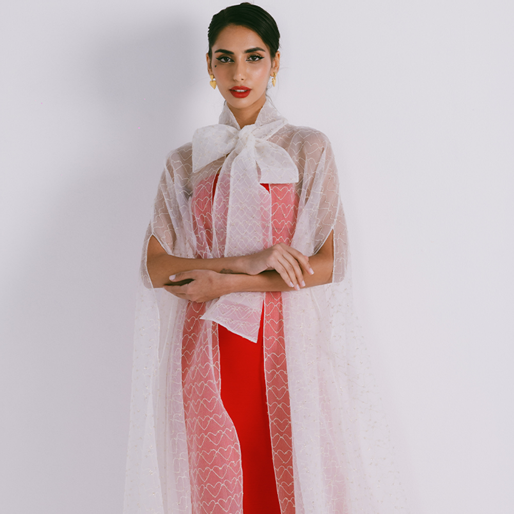 Organza cape with neck bow & heart shaped metallic threads on transparent fabric. Dress sold separately. Explore stylish capes for women. Shop now!