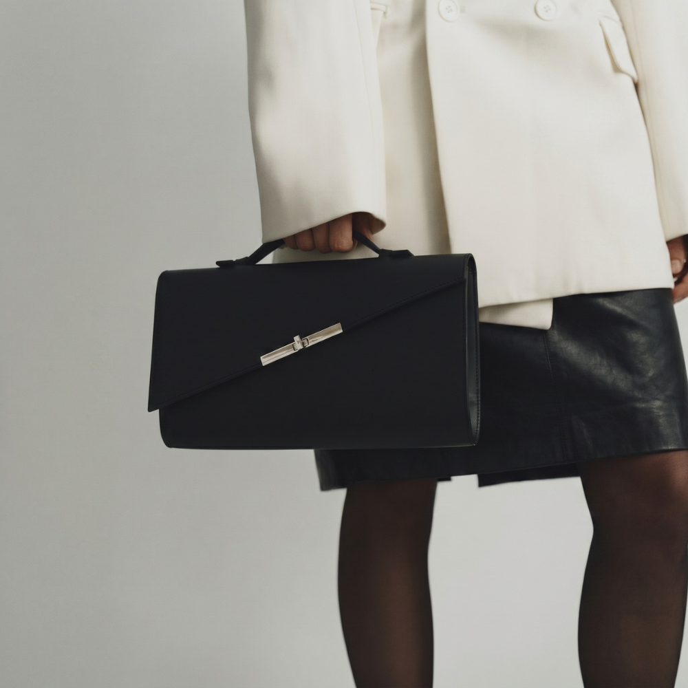 Italian leather clutch with strap and silver hardware, perfect for events. Shop online from our curated edit of premium fashion.