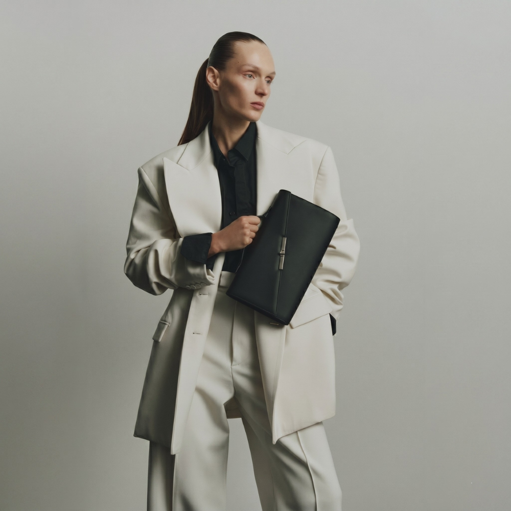 Italian leather clutch with strap and silver hardware, perfect for events. Shop online from our curated edit of premium fashion.