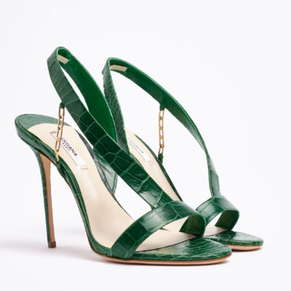 Bold and beautiful,L’Amazone is a high-heel sandal in exotic alligator leather.An asymmetrical strap attached by a gold chain