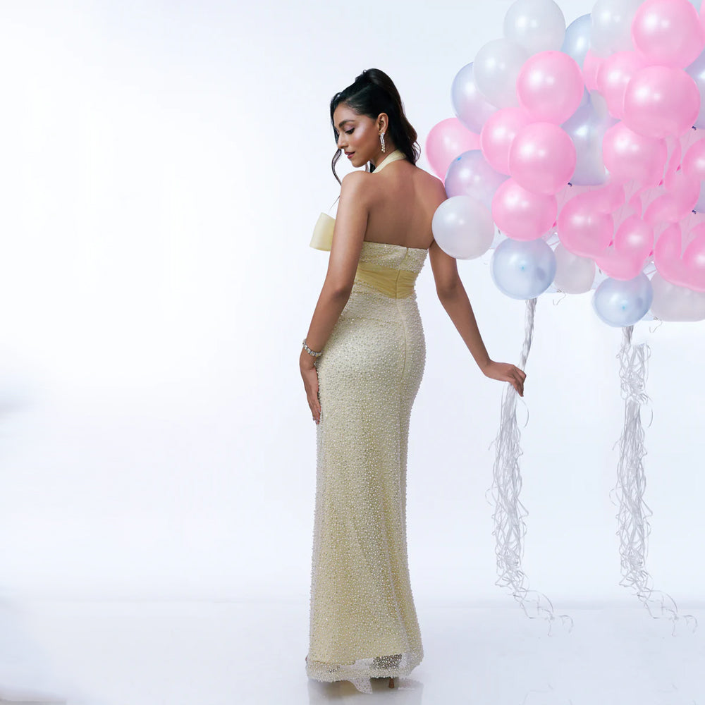 Butter yellow maternity gown with pearl sequin detail and halter neck, perfect for baby showers. Shop online from our curated edit of premium fashion.