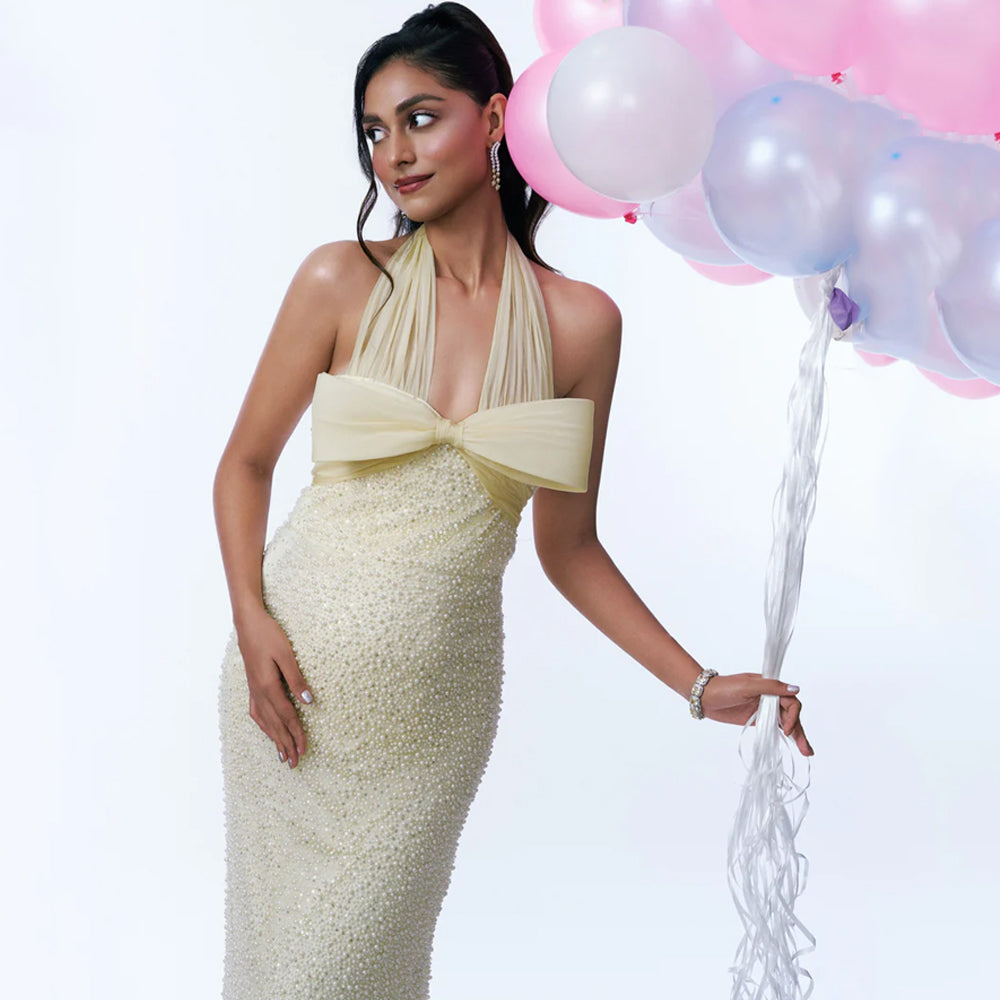 Butter yellow maternity gown with pearl sequin detail and halter neck, perfect for baby showers. Shop online from our curated edit of premium fashion.