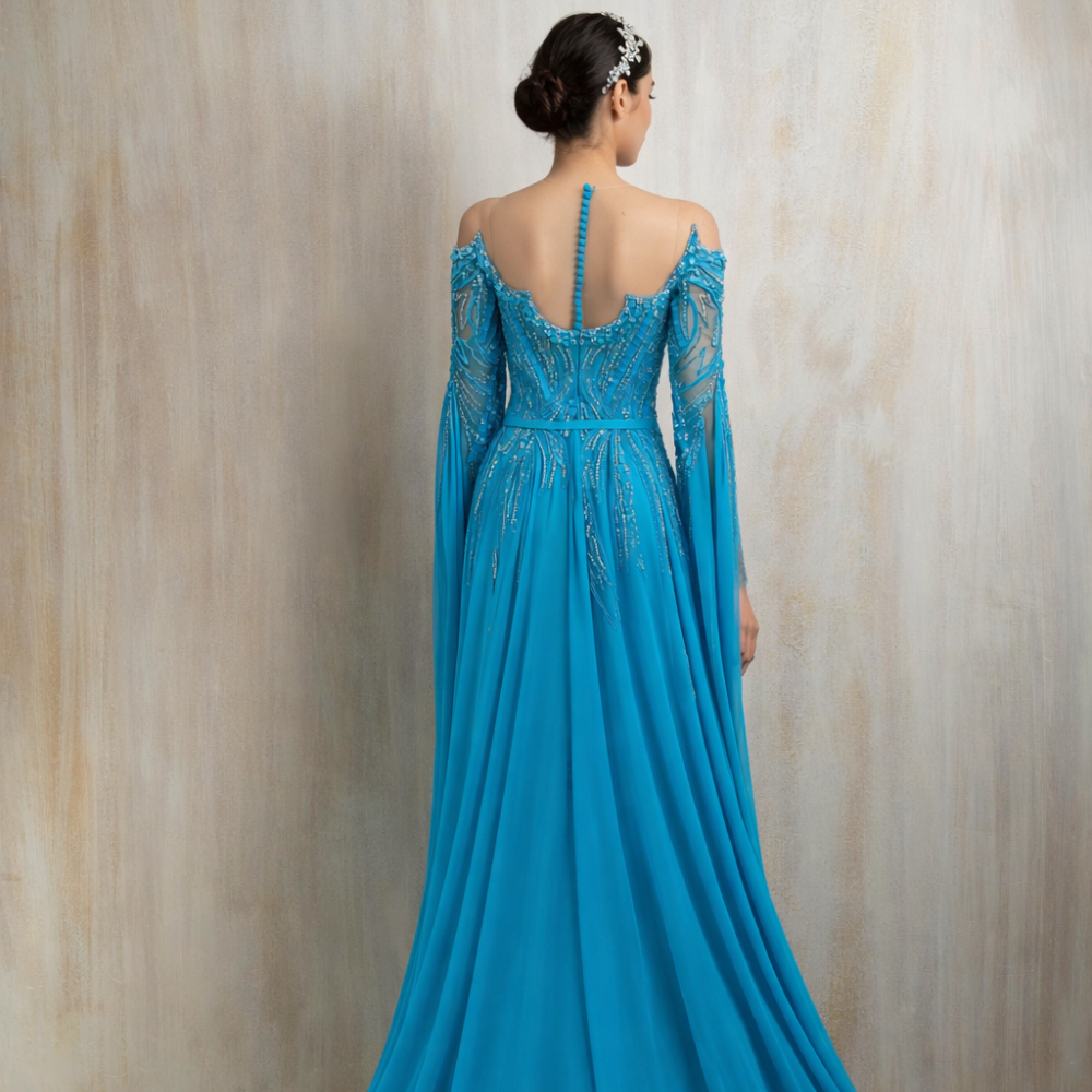 Turquoise embellished gown with a graceful flowing cape, designed for elegant evening occasions. Shop now at our exclusive clothing website.